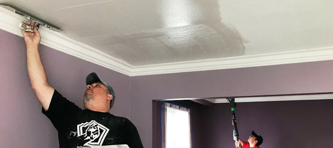 Man applying skim coat to a ceiling